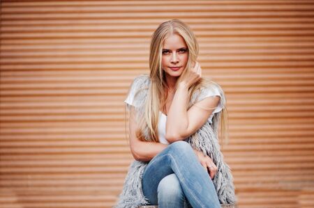 Stylish blonde woman wear at jeans and girl sleeveless with white shirt against shutter background. Fashion urban model portrait.の写真素材