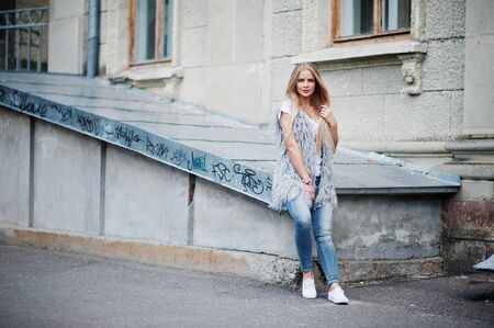 Stylish blonde woman wear at jeans and girl sleeveless with white shirt against street. Fashion urban model portrait.の写真素材