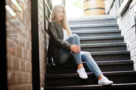 Stylish blonde woman wear at jeans, choker and leather jacket at street near stairs. Fashion urban model portrait.の写真素材