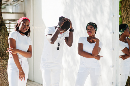 Three stylish african american friends, wear on white clothes. Street fashion of young black people. Black man with two african girls dancing gangsta rap style.の写真素材