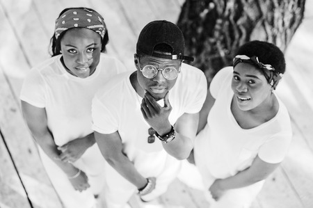 Three stylish african american friends, wear on white clothes. Street fashion of young black people. Black man with two african girls. View from above.の写真素材