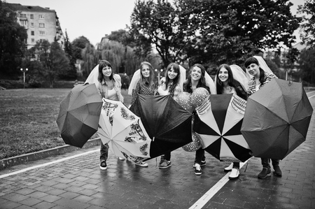 Group of six girls having fun at hen party, with umbrella under rain and balloons.の写真素材