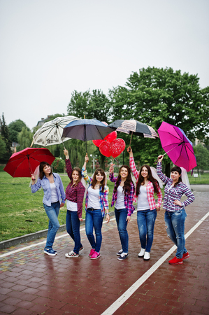 Group of six girls having fun at hen party, with umbrella under rain and balloons.の写真素材