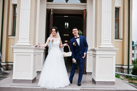 Beautiful wedding couple coming out of the church. Bridesmaid throws candys on her wedding day.の写真素材