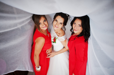 Gorgeous bride with her perfect braidsmaids in her room smiling and discussing wedding.の写真素材