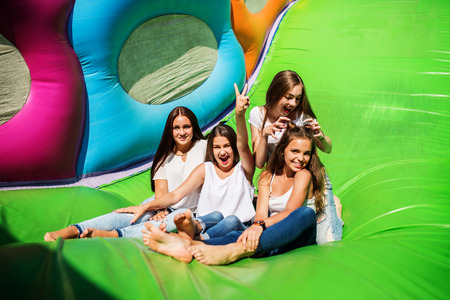 Gorgeous girls having fun on a slide on a sunny day.の写真素材