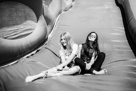 Gorgeous girls having fun on a slide on a sunny day. Black and white photo.の写真素材