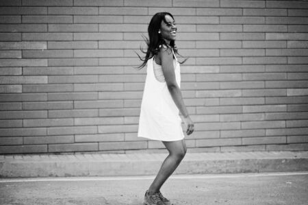 Portrait of a fabulous black african american woman dancing and jumping against brick wall in the background. Black and white photo.の写真素材
