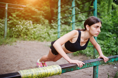 Sport girl at sportswear exercising at horizontal bar exercises in a green park and training at nature. A healthy lifestyle.の写真素材