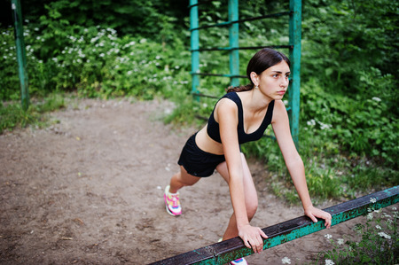 Sport girl at sportswear exercising at horizontal bar exercises in a green park and training at nature. A healthy lifestyle.の写真素材