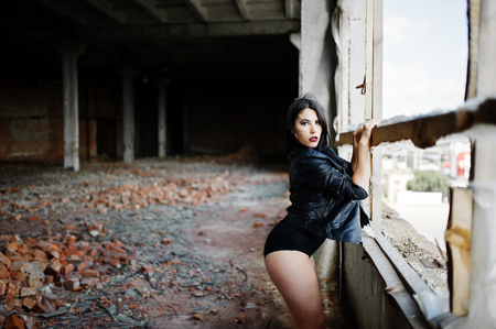 Brunette plus size sexy woman, wear at black leather jacket, lace panties, bra near window at abadoned place.の写真素材