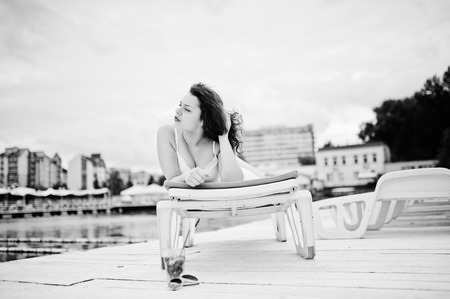Portrait of a very beautiful girl laying and posing on a launger on a lakeside. Black and white photo.の写真素材