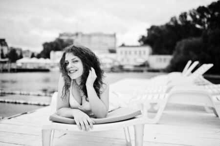 Portrait of a very beautiful girl laying and posing on a launger on a lakeside. Black and white photo.の写真素材