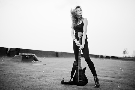 Red haired punk girl wear on black with bass guitar at the roof.の写真素材