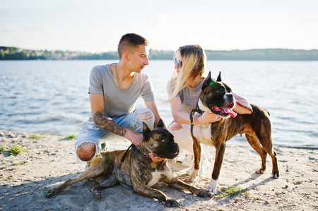 Couple in love with two dogs pit bull terrier against beach side.の写真素材