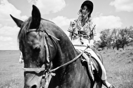 Tow young pretty girls riding a horses on a field at sunny day.の写真素材