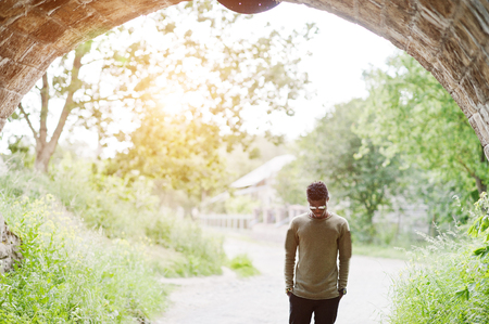 Handsome young african american guy in casual clothing and sunglasses posing and walking in the tunnel.の写真素材