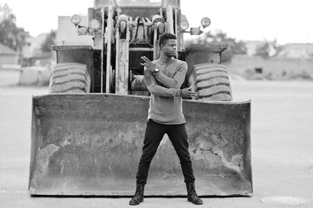 Portrait of an attractive black african american man posing next to the industrial machinery.