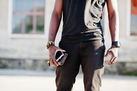 Portrait of a handsome african american guy in black muscle shirt posing in industrial zone.