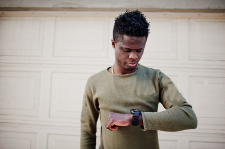 Portrait of an attractive black african american man posing and standing next to the garage gates.