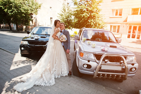 Newlywed standing outside next to two similar suvs.の写真素材