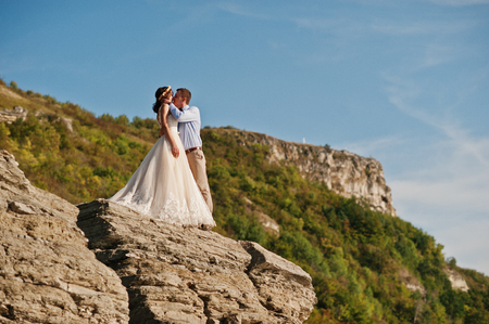 Beautiful wedding couple walking and enjoying each other's company in a rocky district with tall dry grass.の写真素材