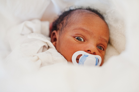 Small tiny newborn african american baby laying on the bed.の写真素材