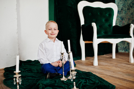 Portrait of an adorable little boy in official clothing posing with candlestick.の写真素材