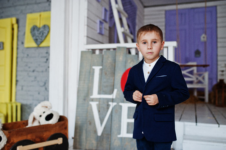 Adorable small boy in stylish clothes posing next to the love sign in the studio.の写真素材