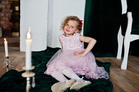 Portrait of a small cute girl in a lovely dress posing with the candlestick in a studio.の写真素材