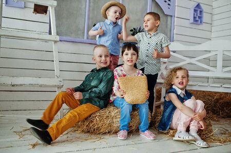 Preschool kids posing outside the house with straw in the rural area.