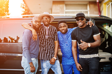 Black men wearing cool traditional clothes stand by the minivan.の写真素材