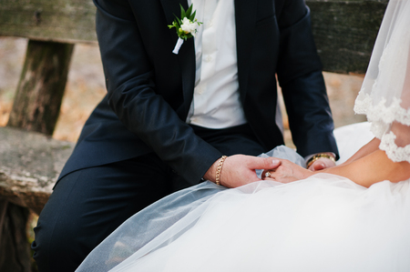 Fantastic wedding couple sitting on the bench in the park on their wedding day.の写真素材