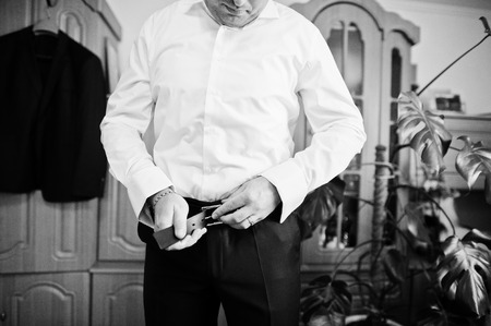 Handsome groom dressing up in his room for his wedding ceremony. Black and white photo.の写真素材