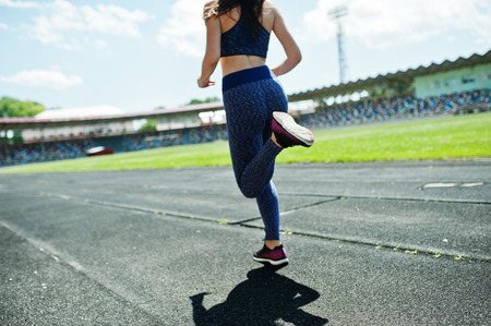 Portrait of a strong fit girl in sportswear running in the stadium.
