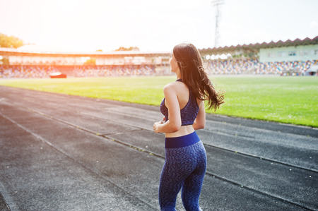 Portrait of a strong fit girl in sportswear running in the stadium.