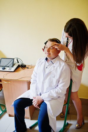 Attractive doctor in white coat examining her patient's health.の写真素材