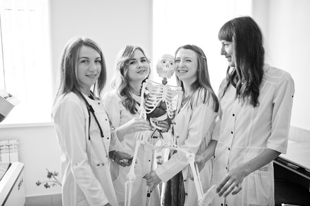 Young doctors having fun by posing with skeleton. Black and white photo.の写真素材