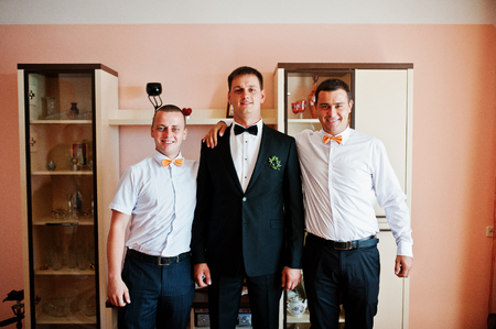 Handsome groom posing with his groomsmen in the room on the wedding day.の写真素材