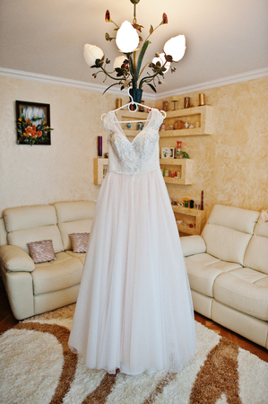 Lovely white wedding dress hanging on the rack on the chandelier in the room.の写真素材