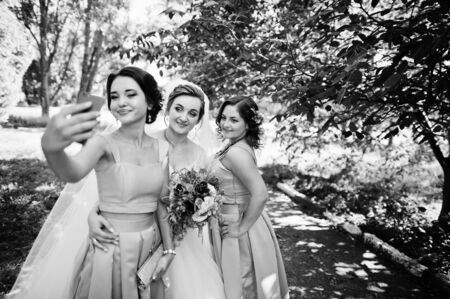 Happy bride having fun with her cool fun bridesmaids in the park on a wedding day. Black and white photo.の写真素材