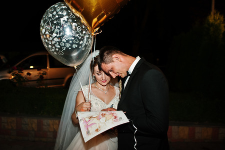 Fantastic wedding couple ;osing with balloons at night outdoors.の写真素材