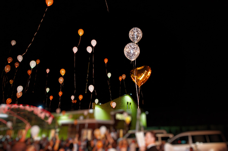 Guests with bride and groom releasing ballons in the air at wedding night.の写真素材