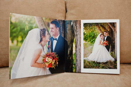 Pages of wedding photobook or wedding album on the sofa with cushions.の写真素材
