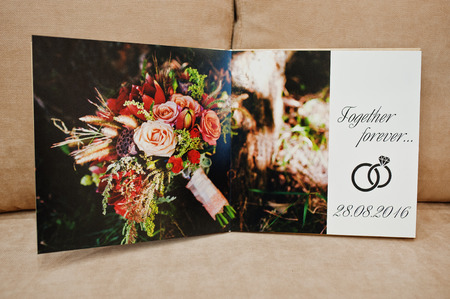 Pages of wedding photobook or wedding album on the sofa with cushions.の写真素材