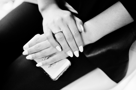 Close-up photo of female manicured hands holding smartphone. Black and white photo.の写真素材