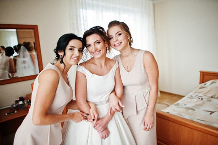 Fabulous young bride posing with her bridesmiads in her room on the wedding day.の写真素材