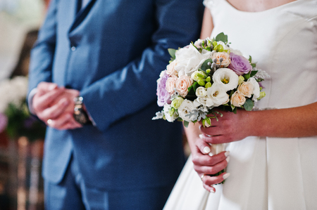 Bride holding a wedding bouquet during the ceremony in the church.の写真素材