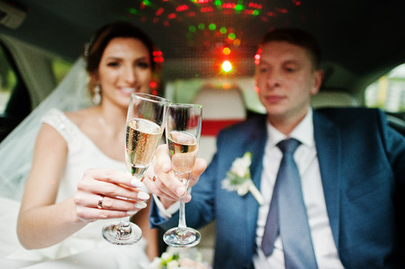 Newly married couple drinking champagne in the limousine on their wedding day.の写真素材