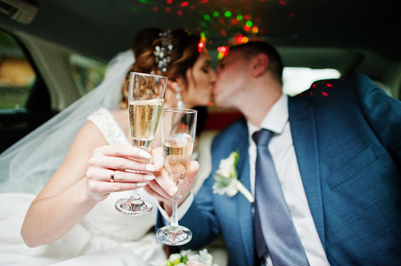 Newly married couple drinking champagne in the limousine on their wedding day.の写真素材